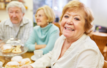 three senior women sitting at a table and smiling